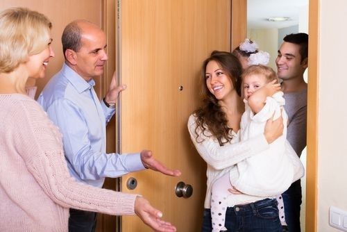 Gezin wordt lachend verwelkomd bij de voordeur van een woning